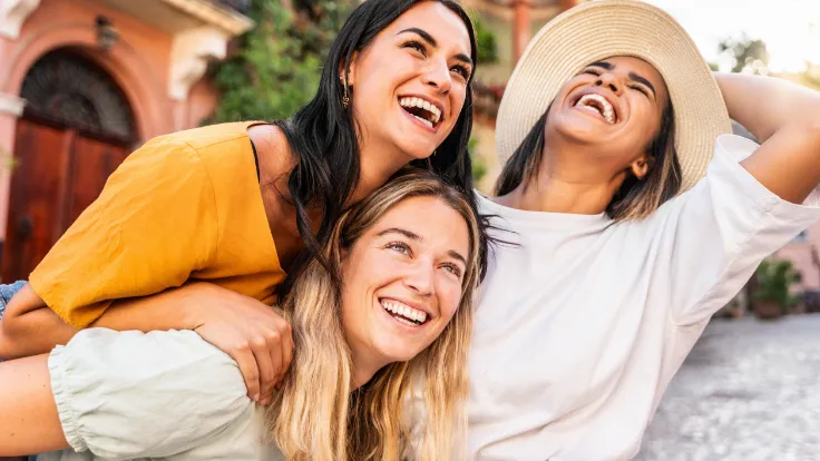 Trzy uśmiechnięte kobiety razem na świeżym powietrzu, letnia scena lifestyle.