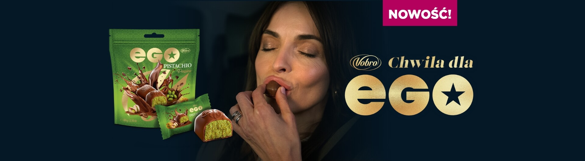 Reklama pralinek EGO Pistachio marki Vobro. Kobieta z zamkniętymi oczami wkłada do ust czekoladową pralinkę. Obok widoczne jest zielone opakowanie produktu, przekrojona pralina z pistacjowym nadzieniem oraz hasło „NEW! Vobro A moment for EGO” na ciemnym tle.